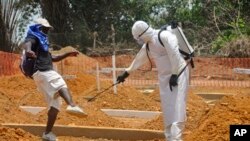 FILE - A man is sprayed with disinfectant at a newly built graveyard for Ebola victims in Monrovia, Liberia, March 2015.