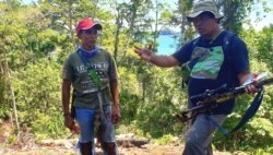 Rosek Nursahid (kanan) dari Profauna memberi penjelasan mengenai larangan berburu di hutan lindung Sendiki di Malang selatan kepada seorang warga (topi merah) yang kedapatan berburu di dalam hutan. (Foto: Petrus Riski/VOA).