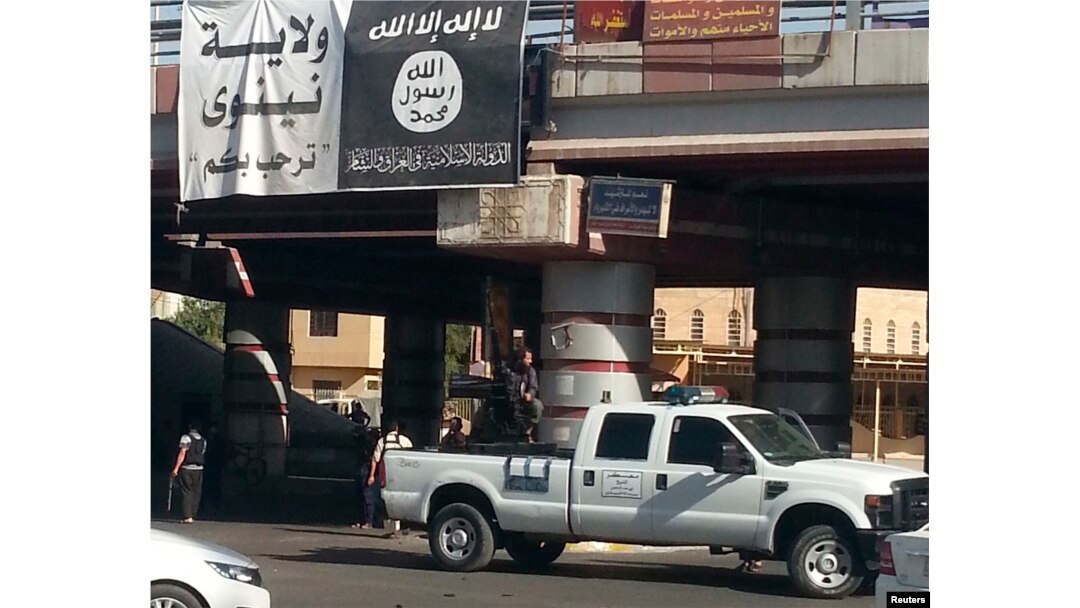 FILE - A fighter from the Islamic State, formerly known as the Islamic State of Iraq and the Levant (ISIL), mans an anti-aircraft gun mounted on the rear of a vehicle in Mosul, Iraq, July 16, 2014.