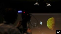A video journalist points his camera at a screen with a rendering during an event organized by Italy's Space Agency, on the occasion of the insertion of the Trace Gas Orbiter into orbit around Mars, and the landing of the Schiaparelli module on the surface of the planet, in Rome, Wednesday, Oct. 19, 2016.