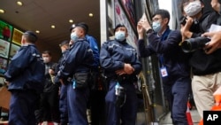 Periodistas toman fotos del allanamiento al periódico digital de Hong Kong "Stand News" mientras la policia custodia el exterior de las oficinas de la redacción el 29 de diciembre de 2021.