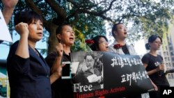 FILE - Supporters of Taiwanese activist Lee Ming-che detained in China, chant their support during a media event in Taipei, Taiwan, Nov. 28, 2017.