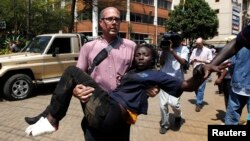 FILE - A journalist rescues a woman injured in a shootout between armed men and police at Nairobi's Westgate shopping mall, Sept. 21, 2013. A new report shows journalists' vulnerability to PTSD after covering extreme violence.
