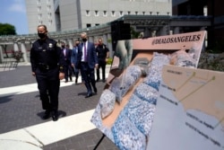 Los funcionarios pasan frente a imágenes de drogas ilegales frente al edificio federal Edward R. Roybal, el jueves 13 de mayo de 2021, en Los Ángeles, California.