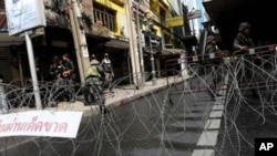 Thai soldiers and riot policemen stand beside barbed wire after they sealed off part of a tourist district on Sukhumvit road in downtown Bangkok, in May.