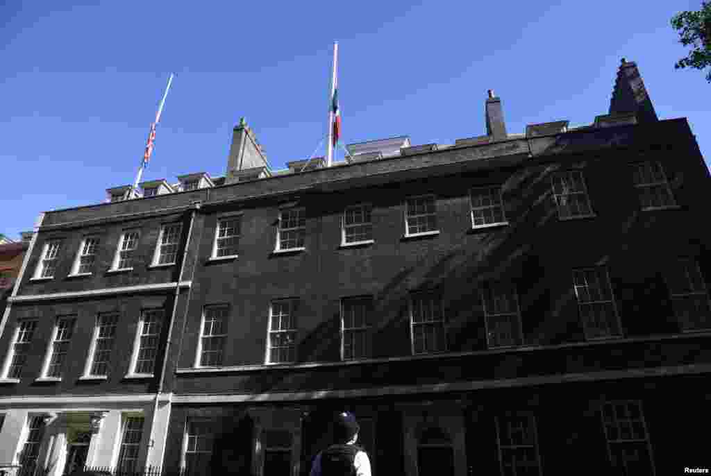 A police officer looks up as France's tricolour hangs at half mast next to Britain's Union Flag on the roof of 10 Downing Street in central London, July 15, 2016.