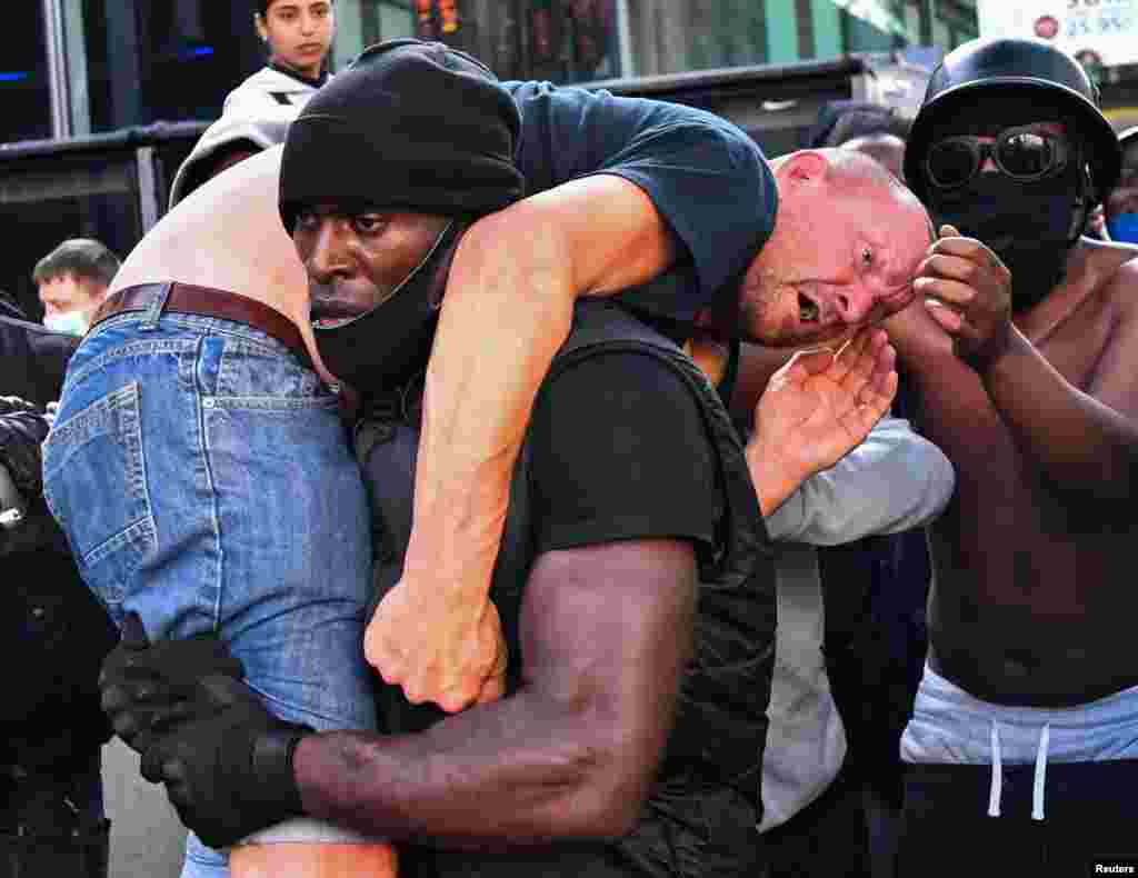 A protester carries an injured counter-protester to safety, near the Waterloo station during a Black Lives Matter protest in London, Britain, June 13, 2020.