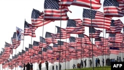 People help with the display of US flags to commemorate the 20th anniversary of 9/11 with the annual Waves of Flags display and remembrance at Pepperdine University in Malibu, California on September 8, 2021.