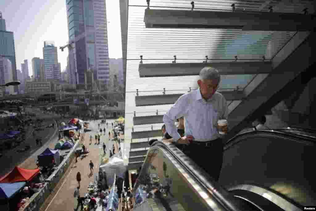 Government employees arrive to work as they walk along an area occupied by protesters outside of the government headquarters building in Hong Kong, Oct. 6, 2014.