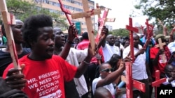People hold wooden crosses to represent those killed in a string of attacks, during a demonstration to demand greater security, in Nairobi, Kenya, Nov. 25, 2014.