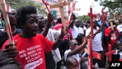 People hold wooden crosses to represent those killed in a string of attacks, during a demonstration to demand greater security on Nov. 25, 2014 in Nairobi.