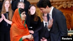 Canada's Prime Minister Justin Trudeau (R) gestures towards Pakistani Nobel Peace Prize laureate Malala Yousafzai after presenting her with honorary Canadian citizenship during a ceremony in the Library of Parliament on Parliament Hill in Ottawa, Canada, April 12, 2017.