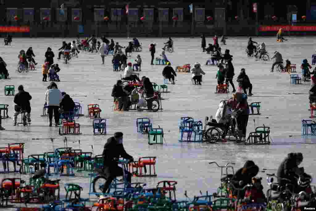 People wearing face masks skate on a frozen lake which has been turned to an ice rink, in Beijing, China.