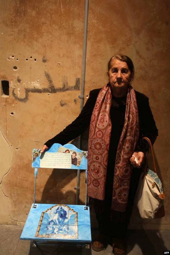 Nohad stands next to an empty chair decorated with a painting of the Virgin Mary and angels, and bearing the portrait of her son Ayman, a Lebanese man who went missing during the Lebanese civil war, during an exhibit in Beirut, April 13, 2017.