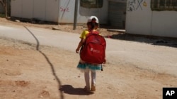 A girl walks to school in the Zaatari Refugee Camp for Syrian refugees, in northern Jordan, Aug. 6, 2017. 