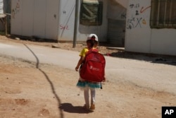 FILE - A girl walks to school in the Zaatari Refugee Camp for Syrian refugees, in northern Jordan, Aug. 6, 2017.