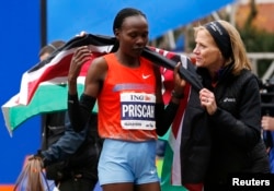 Priscah Jeptoo (L) of Kenya is wrapped in the Kenyan flag by Mary Wittenberg, president of the New York Road Runners, after Jeptoo crossed the finish line to win the women's division of the New York City Marathon, Nov. 3, 2013.