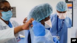 FILE - Medical personnel adjust their personal protective equipment while working in the emergency department at NYC Health + Hospitals Metropolitan in New York, May 27, 2020. 