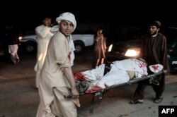 Afghan men carry a wounded man into a hospital following a car bomb explosion in Lashkargah, capital of Helmand province, Afghanistan, March 23, 2018.