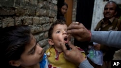 FILE - A Pakistani health worker gives a polio vaccine to a child in Islamabad, Dec. 8, 2014.