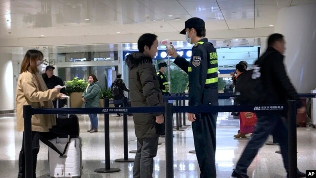 中国湖北省武汉市天河国际机场工作人员测试旅客的体温。（2020年1月21日）