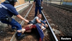 Mađarski policajci pokušavaju da uklone porodic sa šina na železničkoj stanici u gradu Bičke
