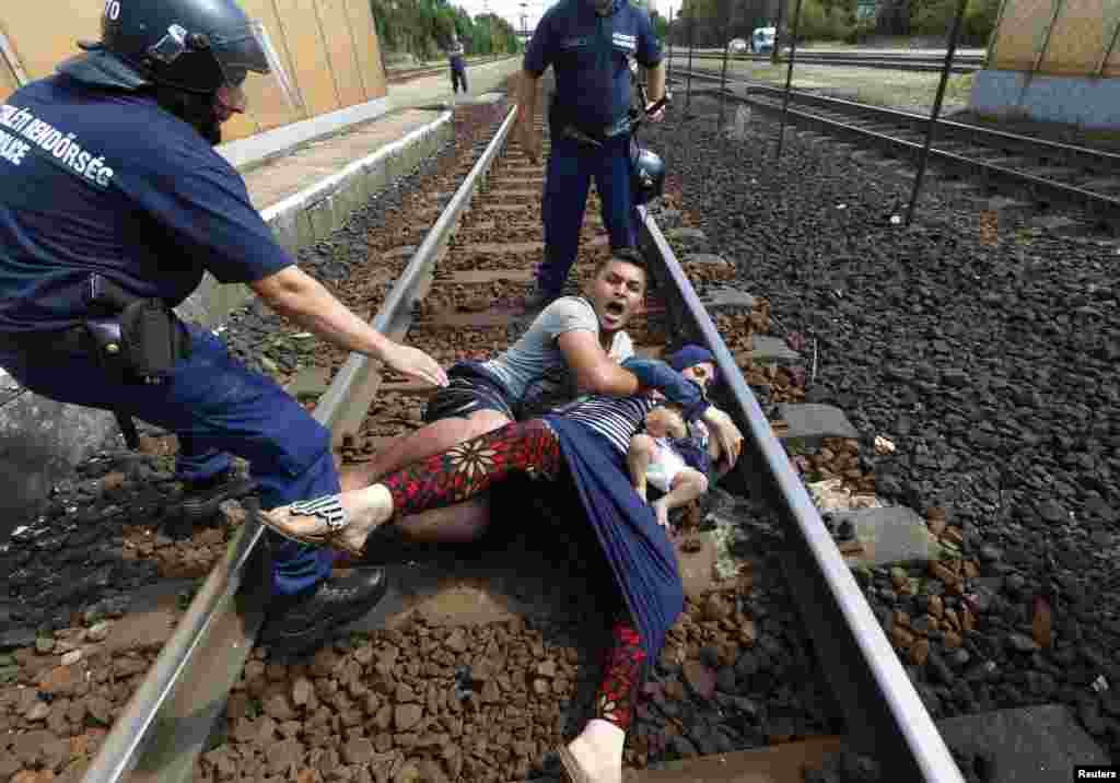 Hungarian policemen stand by the family of migrants as they wanted to run away at the railway station in the town of Bicske, Sept. 3, 2015.