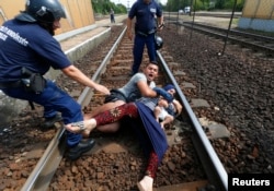 Hungarian policemen stand by the family of migrants as they wanted to run away at the railway station in the town of Bicske, Hungary, Sept. 3, 2015.