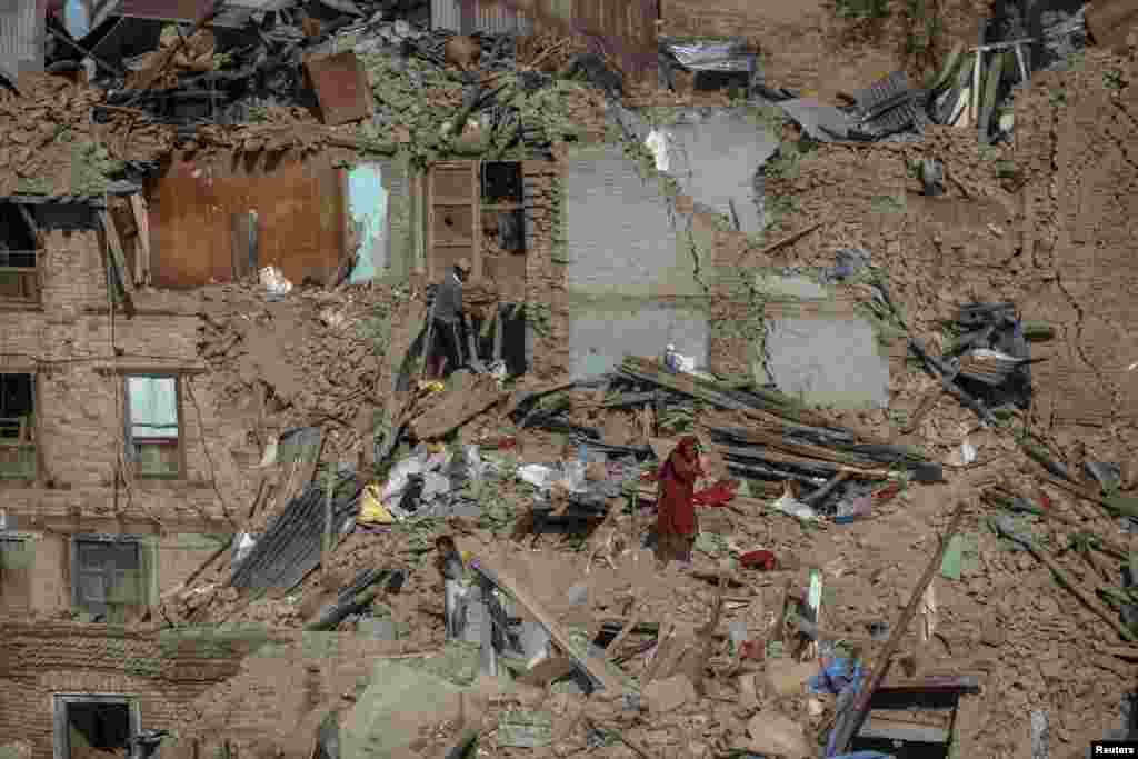 Penyintas gempa bumi mencari barang-barang milik mereka di rumah-rumah yang runtuh di Sankhu, di pinggiran Kathmandu, Nepal.