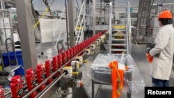 Un trabajador labora con robots en la fábrica de Procter & Gamble en Tabler Station, Virginia Occidental, EE. UU., el 28 de mayo de 2021. 