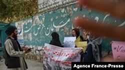 Seorang anggota pasukan Taliban berbicara dengan perempuan yang melakukan unjuk rasa di luar salah satu sekolah di Kabul, Afghanistan, pada 30 September 2021. (Foto: AFP/Bulent Kilic)