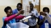 Uma delegada eleitoral mostra um boletim de voto durante a contagem no fim das eleições gerais em Luanda, Angola, 13 de Agosto 2017 (arquivo)