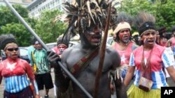 Papuan activists in traditional costumes and shirts painted with the colors of 'Morning Star' separatist flag take part in a rally marking the 50th anniversary of failed efforts by Papuan tribal chiefs to declare independence from Dutch colonial rule in 1