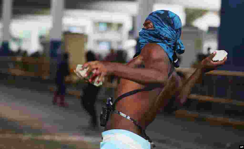 Um manifestante atira pedras contra a polícia, fora da estação central de comboios, durante um protesto contra o aumento das tarifas de autocarro no Rio de Janeiro, Fev. 6, 2014. 