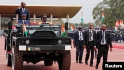 Ivory Coast's President Alassane Ouattara salutes while standing in a military vehicle during a parade to commemorate the country's 56th Independence Day outside the presidential palace in Abidjan, Aug. 7, 2016. 