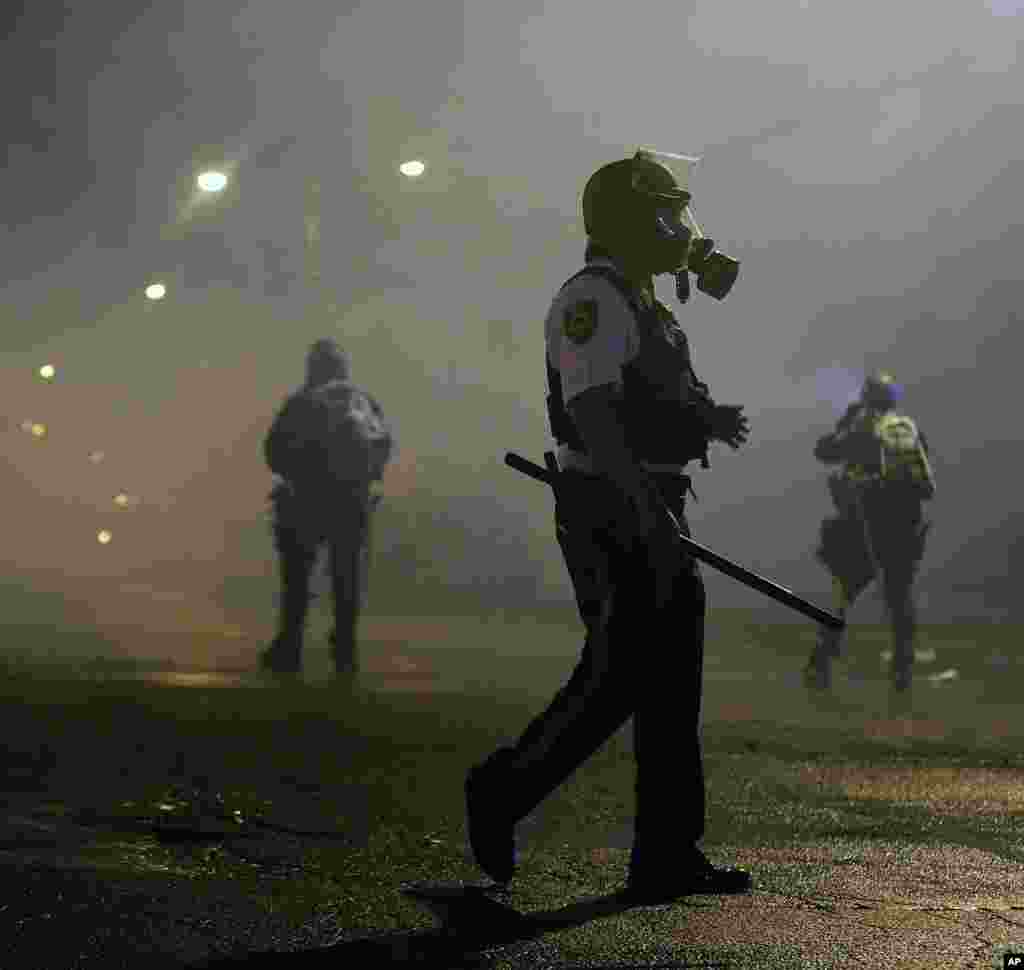 Law enforcement officers wait to advance, Aug. 17, 2014, after firing tear gas to disperse a crowd in Ferguson.