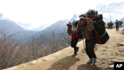 FILE - Nepalese porters carry heavy loads for climbers on their way to Everest Base Camp at Kyangjuma, Nepal in this April 7, 2015 photo.. 