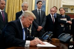 White House chief strategist Steve Bannon (far right) is among the top policy advisers present as President Donald Trump signs an executive order in the Oval Office, Jan. 23, 2017.