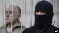 Olexiy Pukach, left, in a defendant's cage on the final day of his trial in Kiev, Ukraine, Jan. 29, 2013.