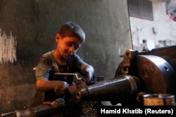 Issa, 10 years old, measures a mortar shell on a machine in a weapons factory of the Free Syrian Army in Aleppo, September 7, 2013. Issa works with his father in the factory for ten hours every day except on Fridays.