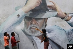 Fans of Indian superstar Rajinikanth offer prayers in front of his poster outside a cinema hall to celebrate the screening of “Kabali” in Chennai, India, Friday, July 22, 2016.