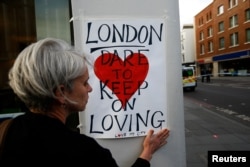 A woman attaches a sign near London Bridge, after attackers rammed a hired van into pedestrians on London Bridge and stabbed others nearby killing and injuring people, in London, Britain June 4, 2017.
