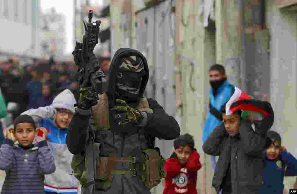 A Palestinian militant fires into the air during the funeral of 23-year-old Palestinian Mohammed Adwan, who was killed during a clash with Israeli forces near Jerusalem overnight, in the Qalandia refugee camp near Ramallah in the West Bank.