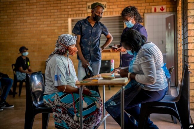 FILE - People are processed before receiving their shot against COVID-19 Friday Dec. 3, 2021 at the Orange Farm, South Africa, multipurpose center. (AP Photo/Jerome Delay)