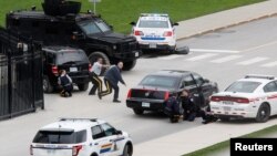 Police officers take cover near Parliament Hilll following a shooting incident in Ottawa, Canada. 