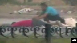 A protester crouches near the body of a man lying on the ground in Hama in this still image taken from video posted on a social media website on August 4, 2011 (Reuters cannot independently verify the content of the video)