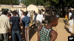 10일 나이지리아 포티스쿰시의 고등학교에서 폭탄테러가 발생한 가운데, 주민들이 테러 현장 주변에 모여있다.