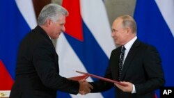 FILE - Russian President Vladimir Putin (R) and Cuban President Miguel Diaz-Canel, exchange documents after their talks in the Kremlin, in Moscow, Russia, Nov. 2, 2018.