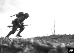 Pfc. Paul Ison from the 6th Marine Division dashes forward through Japanese machine-gun fire while crossing a draw on Okinawa, May 10, 1945.