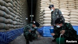 FILE - Soldiers check rice stocks at a warehouse in Ayutthaya province, north of Bangkok, Thailand, July 3, 2014. Thailand plans to sell the remaining 11.4 million tons of rice in government stockpiles within two months.